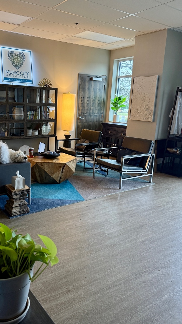 Music City Ketamine lobby with the clinic logo above the display cabinet and a dog resting on the couch